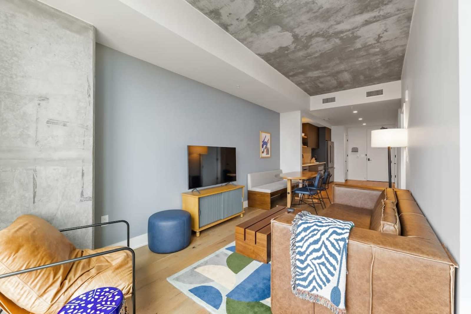 Living room of unit 2006 at Natiivo Austin with a sofa, media console and exposed concrete ceiling