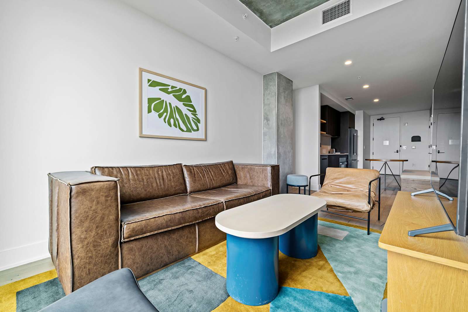 Studio living area in unit 1204 at Natiivo Austin with a leather sofa, sculptural coffee table and a colourful rug