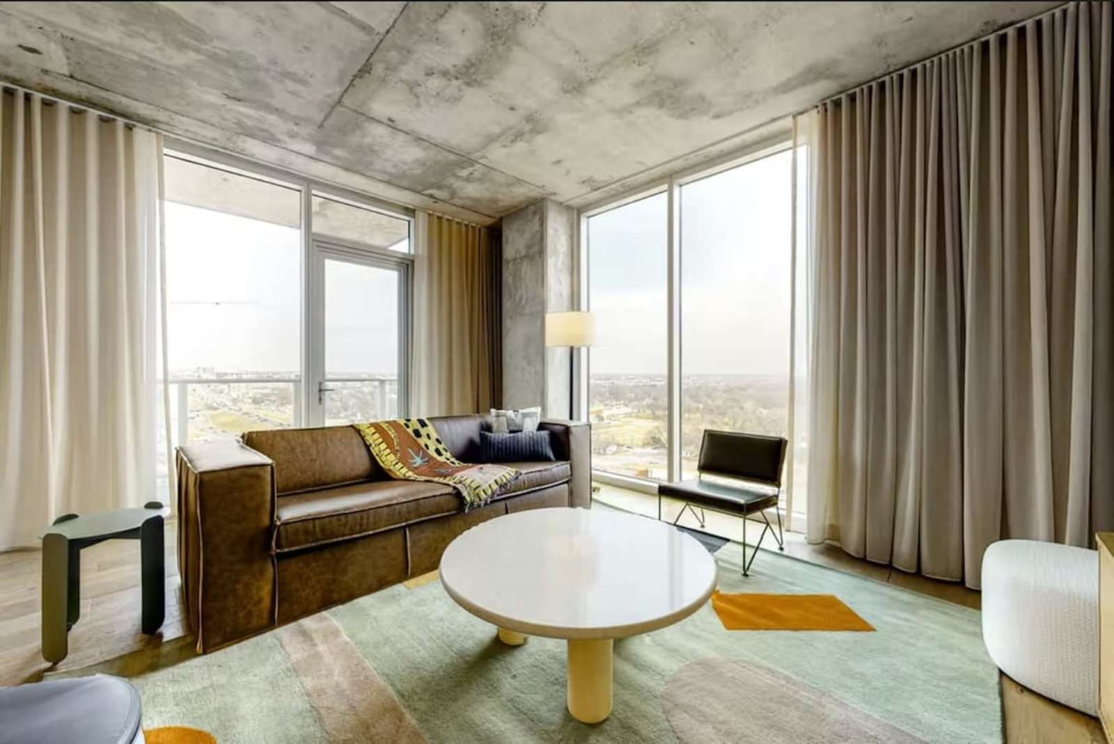 Living room of unit 1205 at Natiivo Austin with a leather sofa, round table and full-height windows over the city