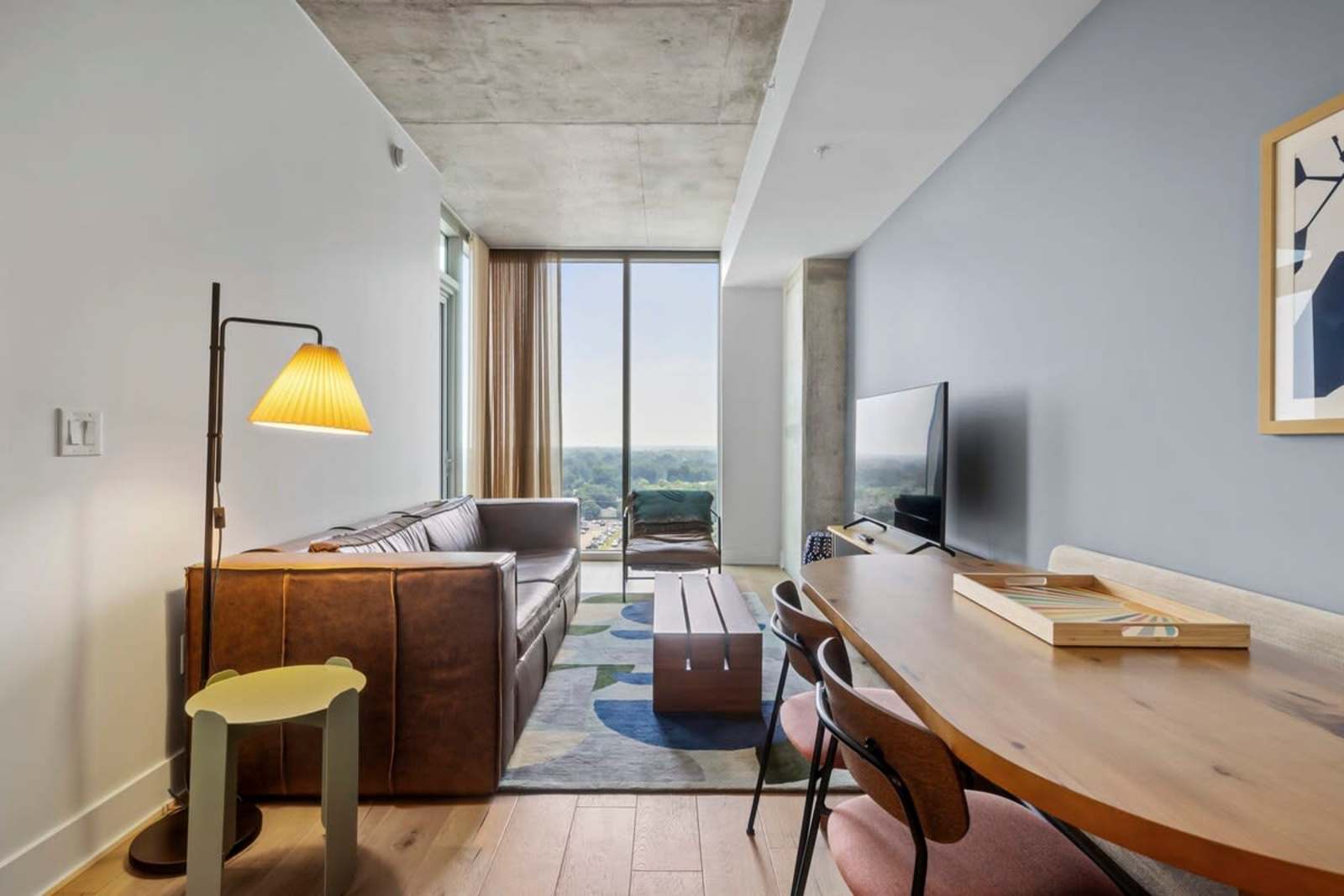 Living room and desk in unit 1409 with a leather chair, lamp and windows along the wall