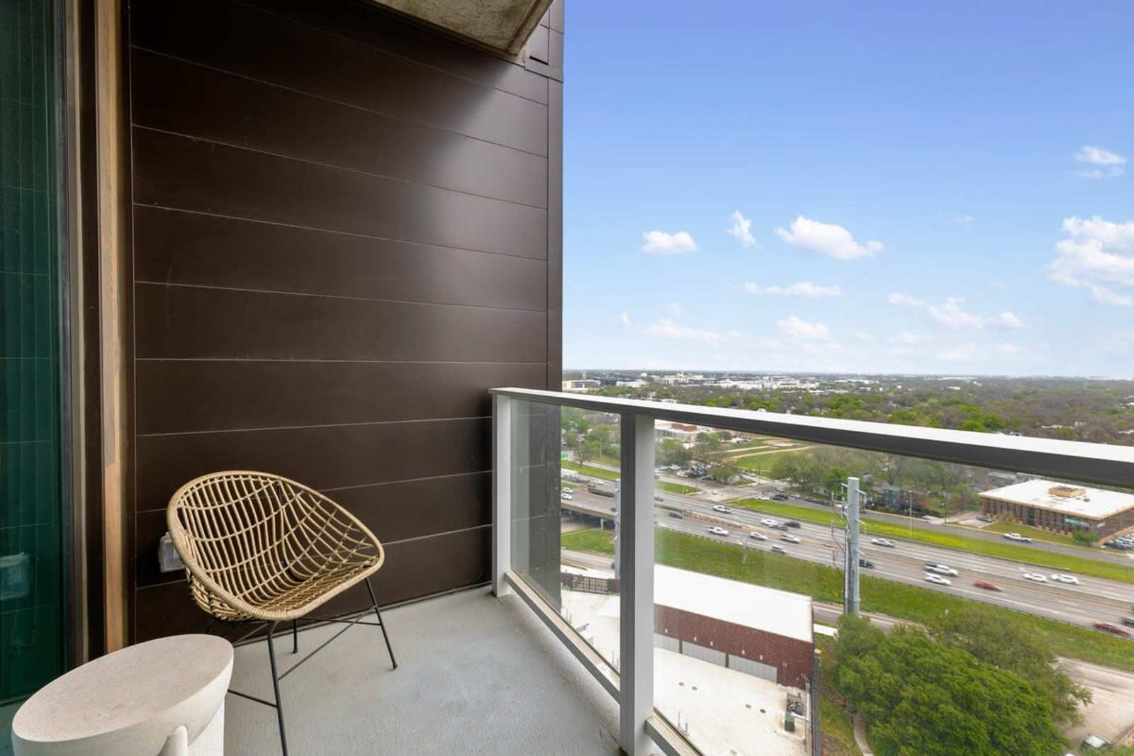 Balcony of unit 2006 with a woven chair, looking out across Austin from the highest floor in the collection
