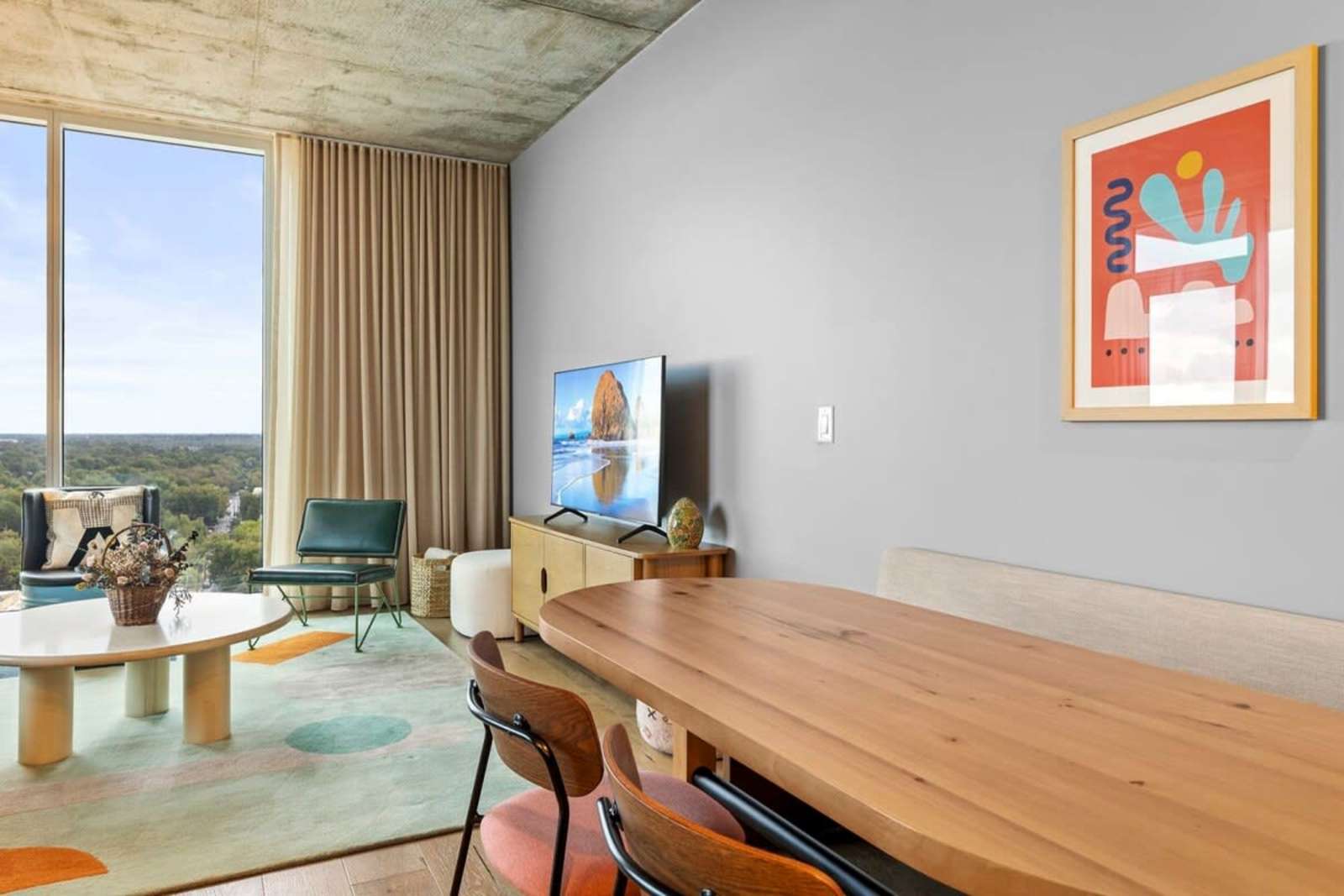 Living and dining area of unit 1804 seen from the kitchen, with the TV and window wall beyond