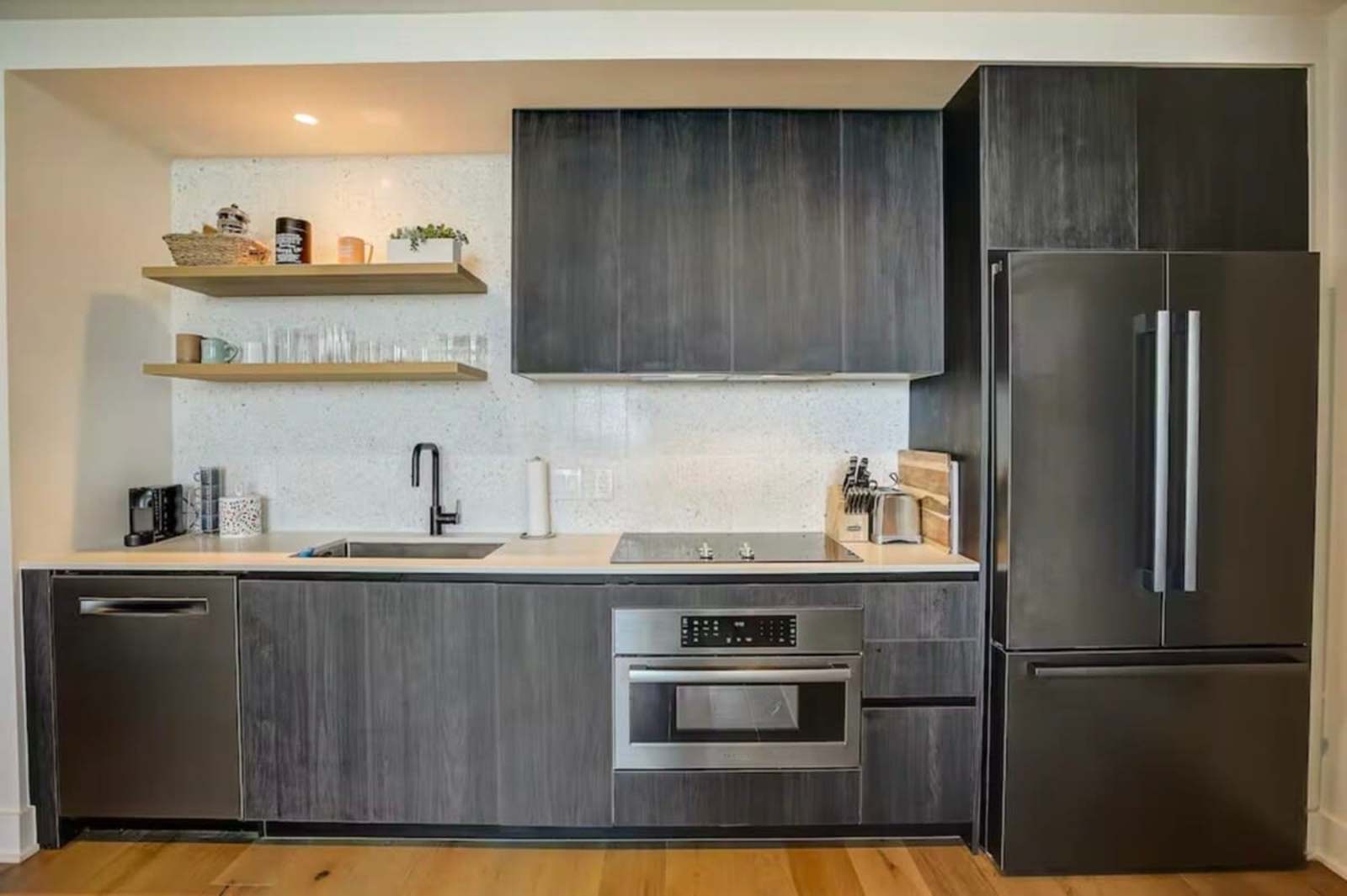 Kitchen in unit 1504 with dark cabinetry, sink, induction cooktop, wall oven and full-height refrigerator