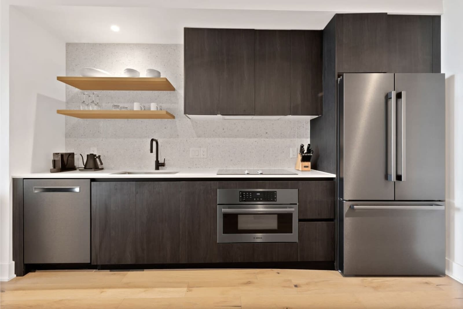 Kitchen in unit 2006 with dark cabinetry, open shelving, induction cooktop, wall oven and refrigerator