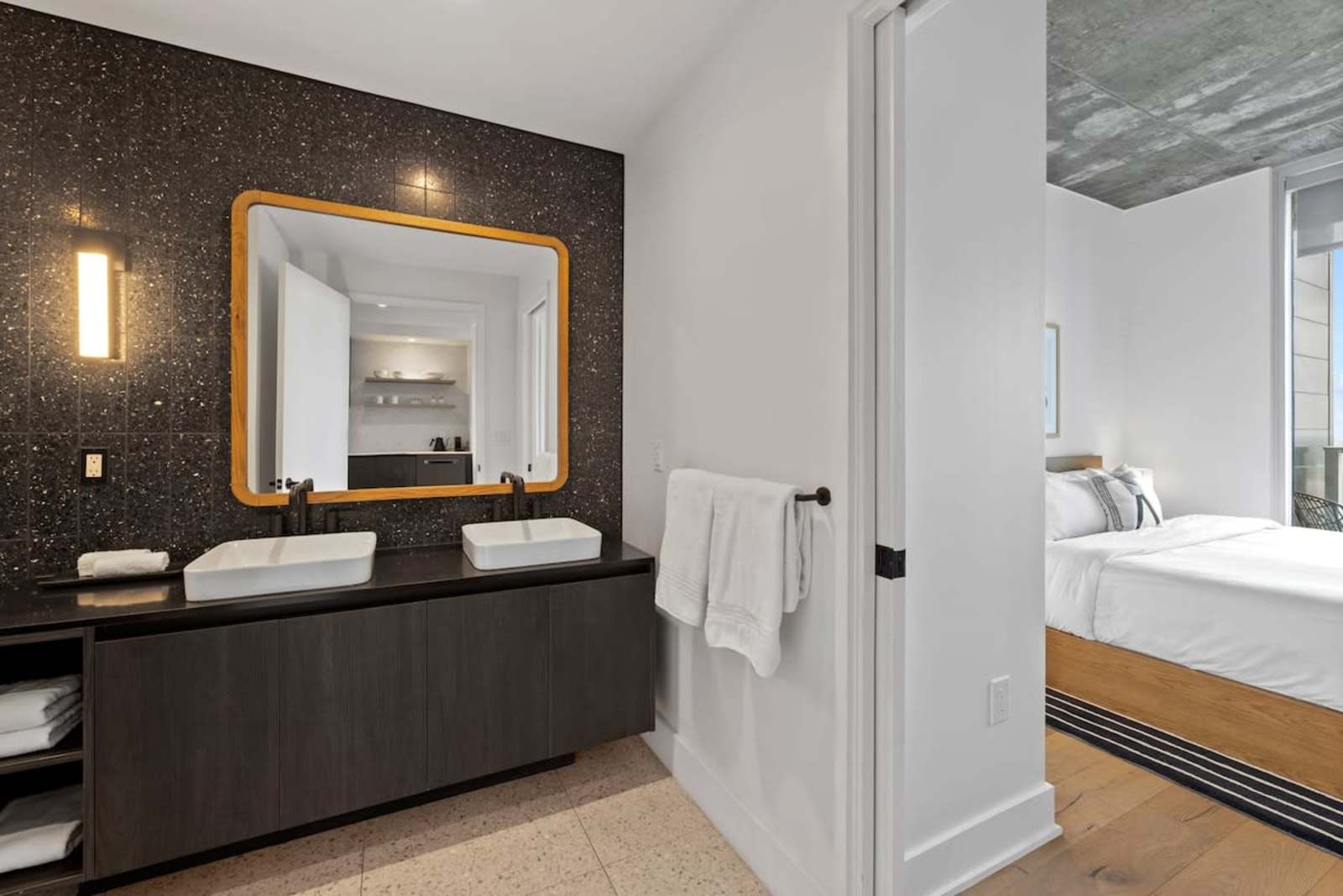 Bathroom in unit 2006 with a vessel sink, brass-framed mirror and a view through to the bedroom