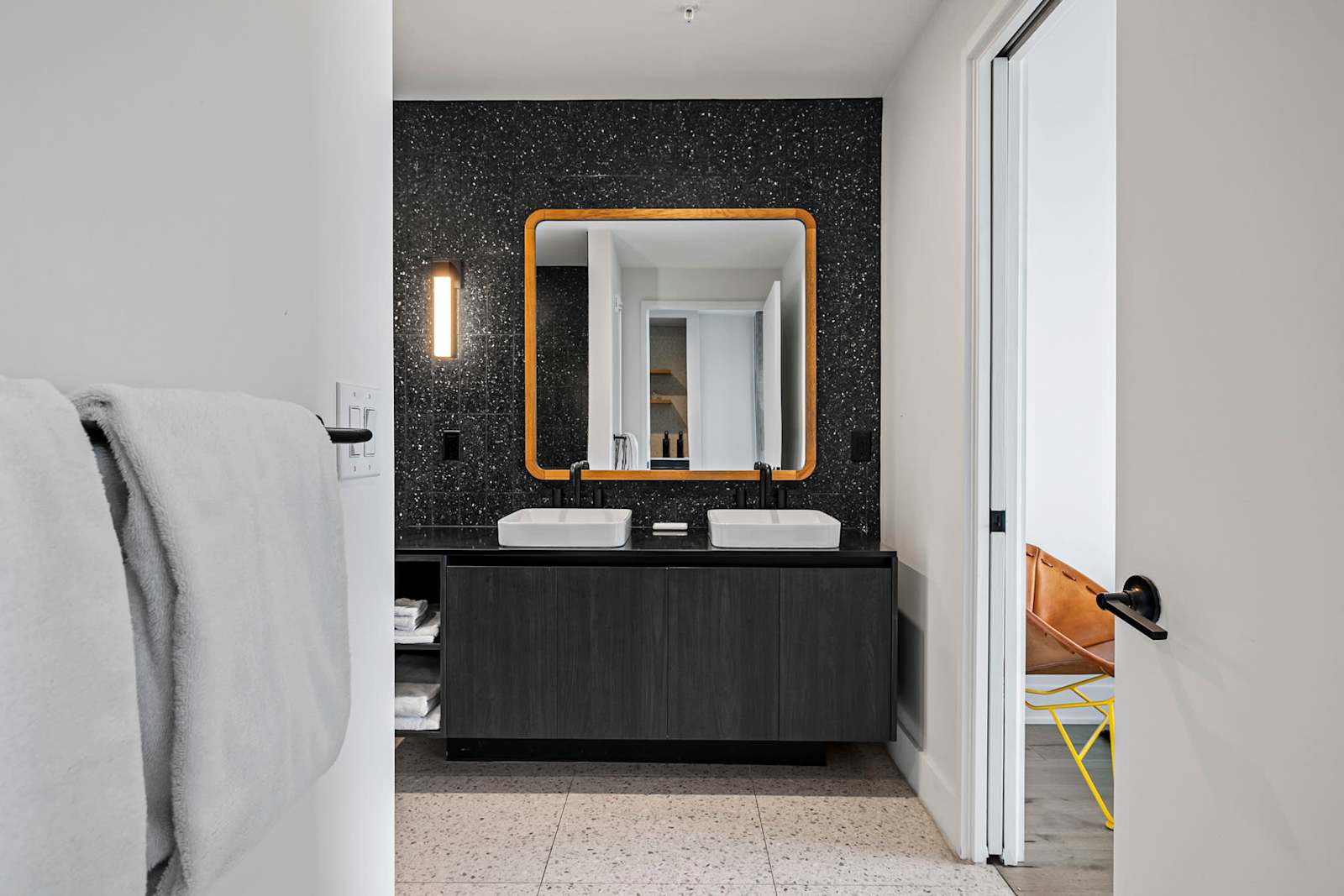 Bathroom in unit 1204 with a vessel sink, brass-framed mirror and dark stone wall