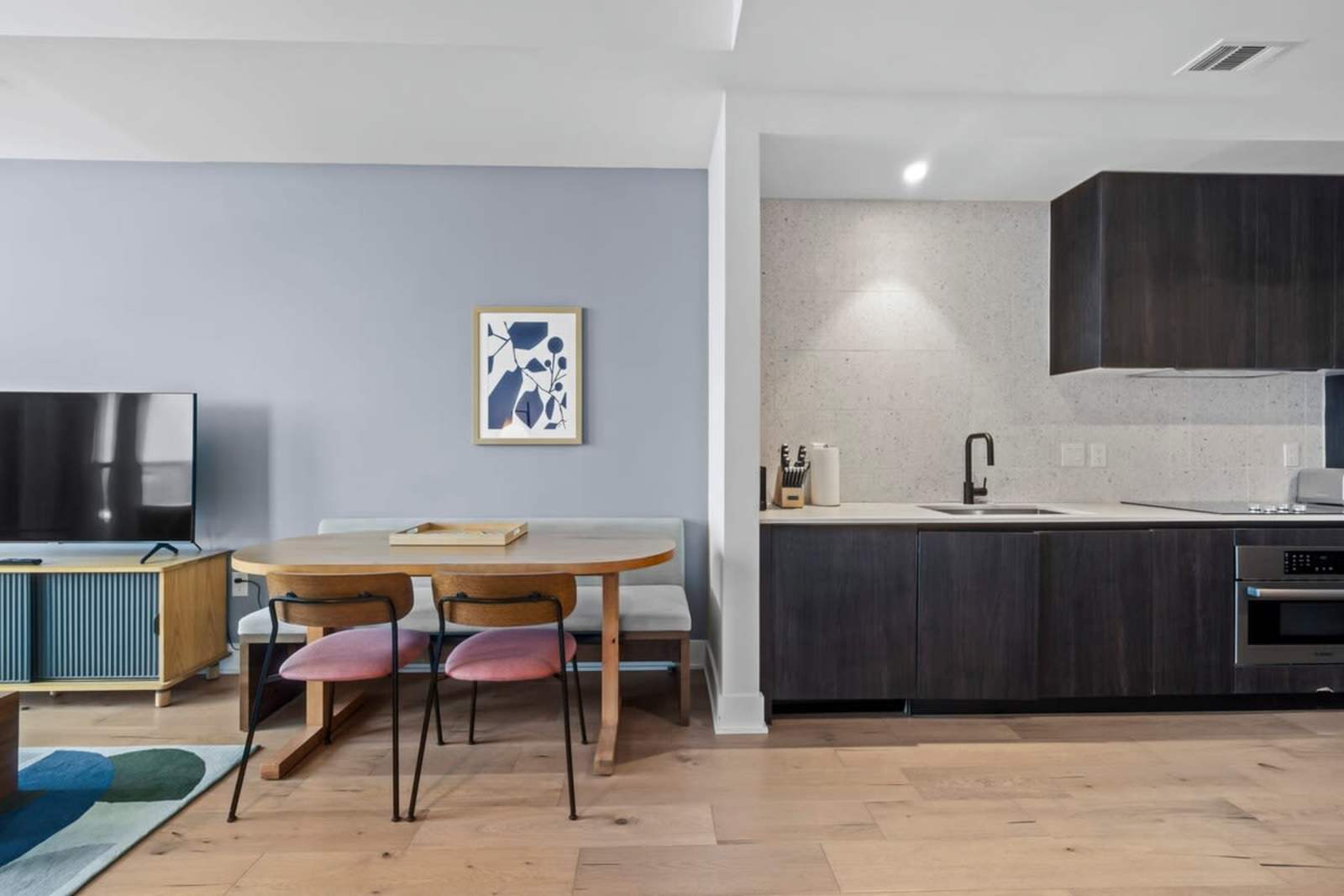 Dining table and kitchen in unit 1409 seen from the living room, with the TV on the left