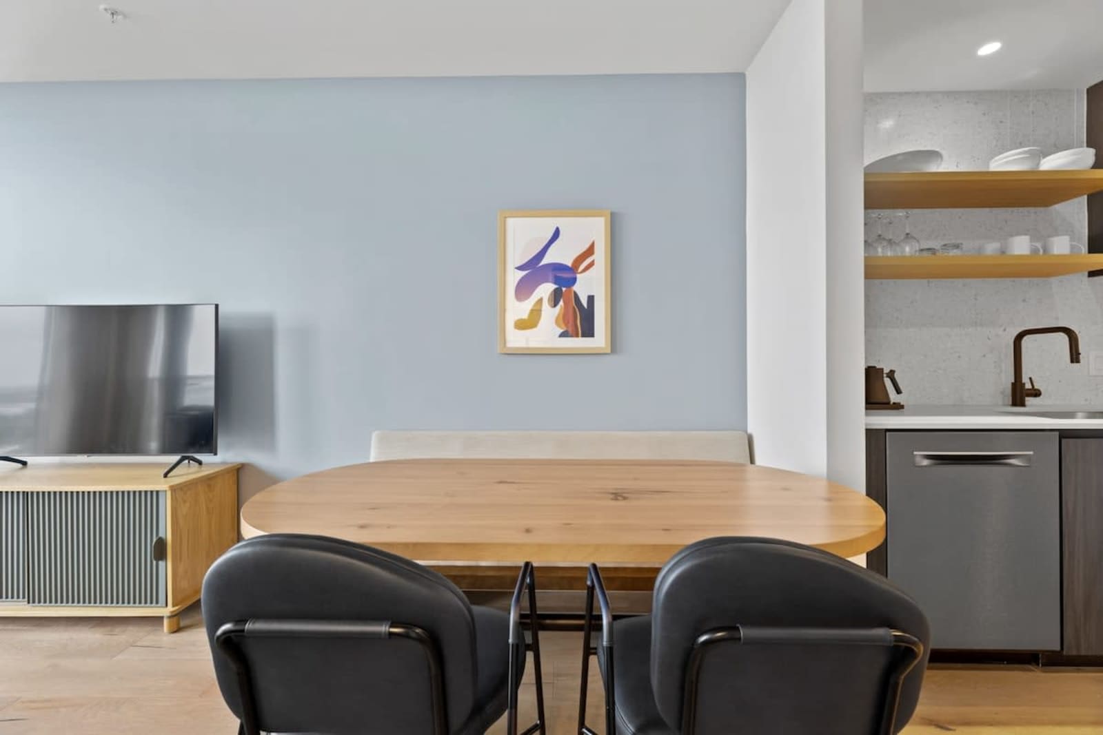 Dining table in unit 2006 with two chairs, framed artwork and the kitchen counter behind