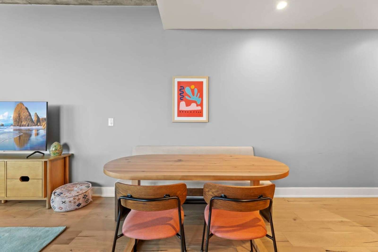 Dining corner of unit 1804 with an oak table, pink chairs and a low console