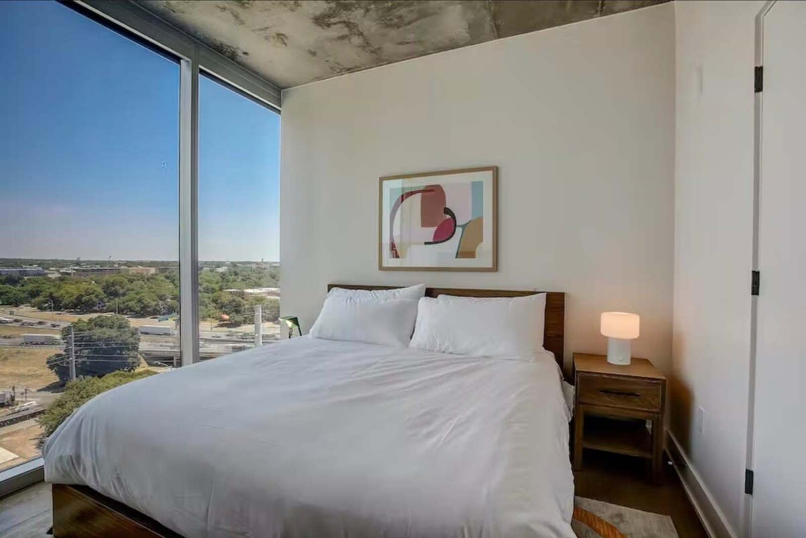 King bed in unit 1504 with a wide window and long views across the tree line