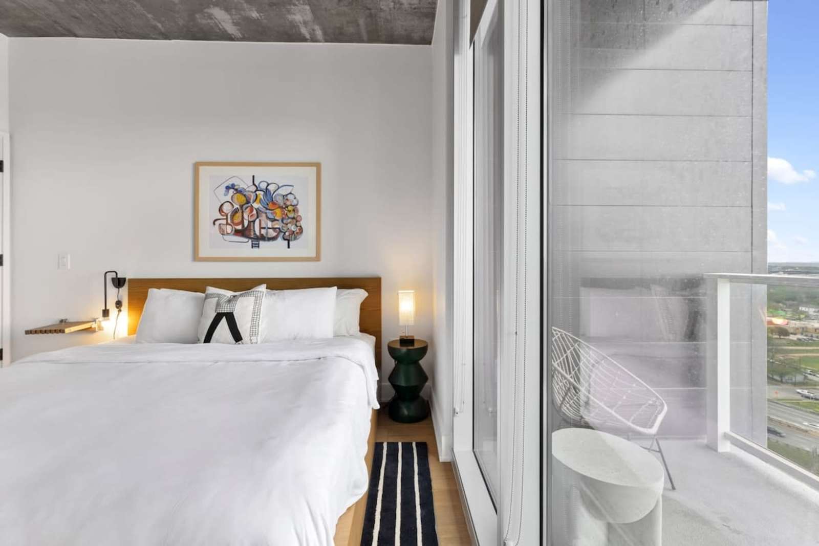 Bedroom in unit 2006 with white linens and a window looking out over downtown Austin