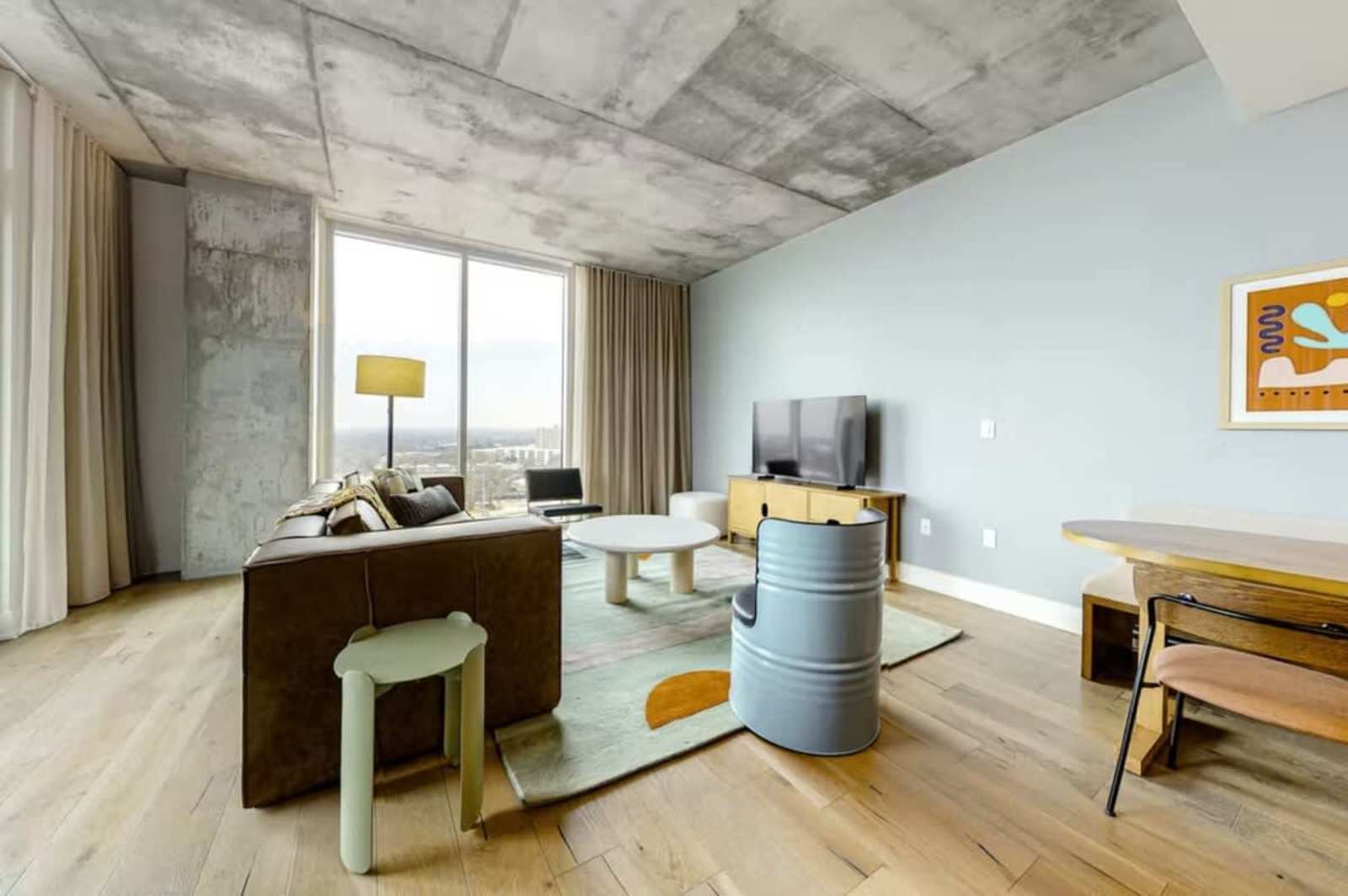 Workspace and lounge corner in unit 1205 with a desk, TV and windows facing downtown