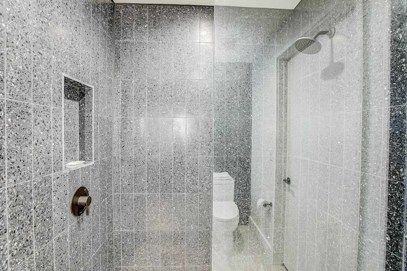Walk-in shower in unit 1406 finished in speckled grey stone tile