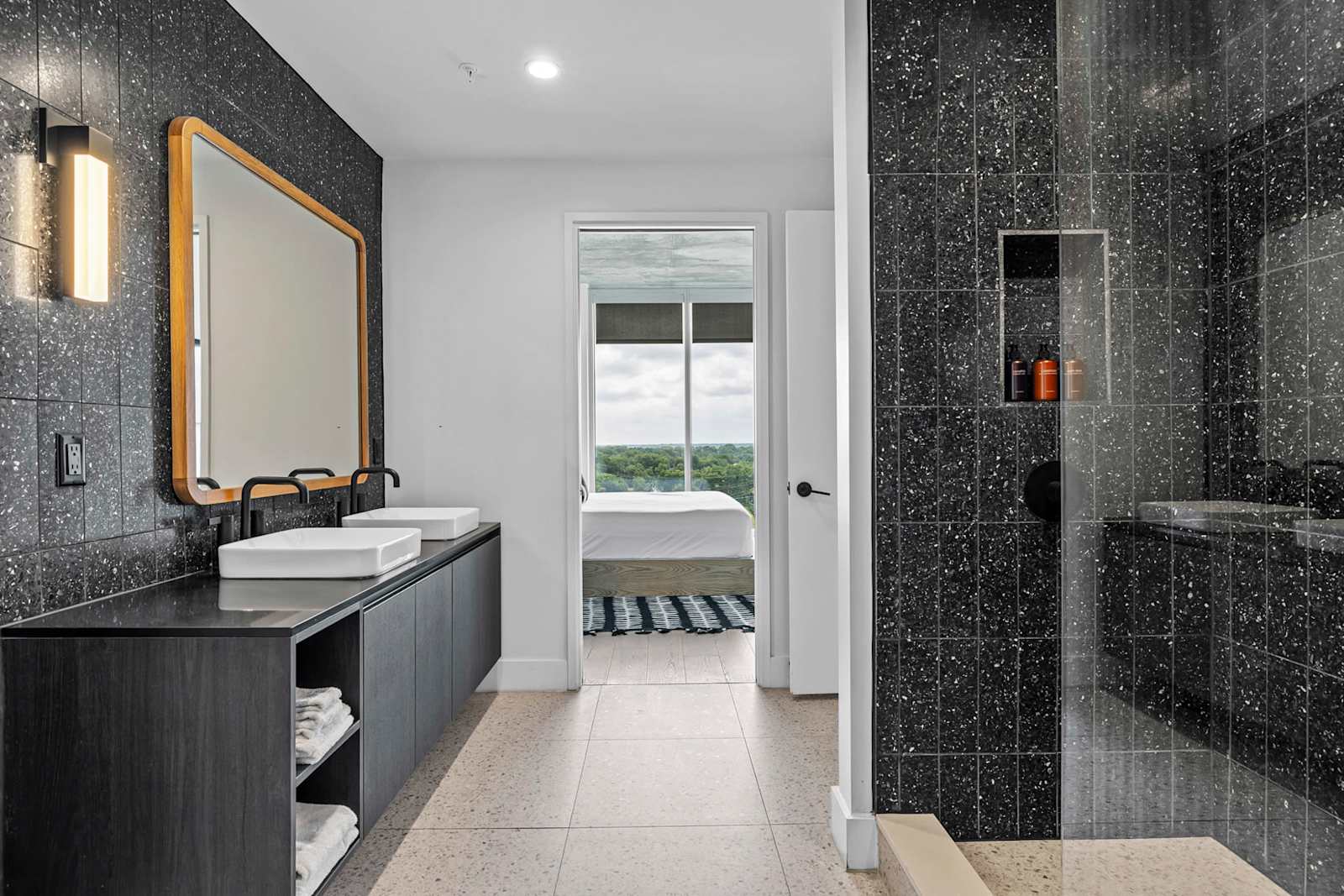 Bathroom in unit 1204 with a walk-in glass shower, long vanity and a view back into the sleeping area