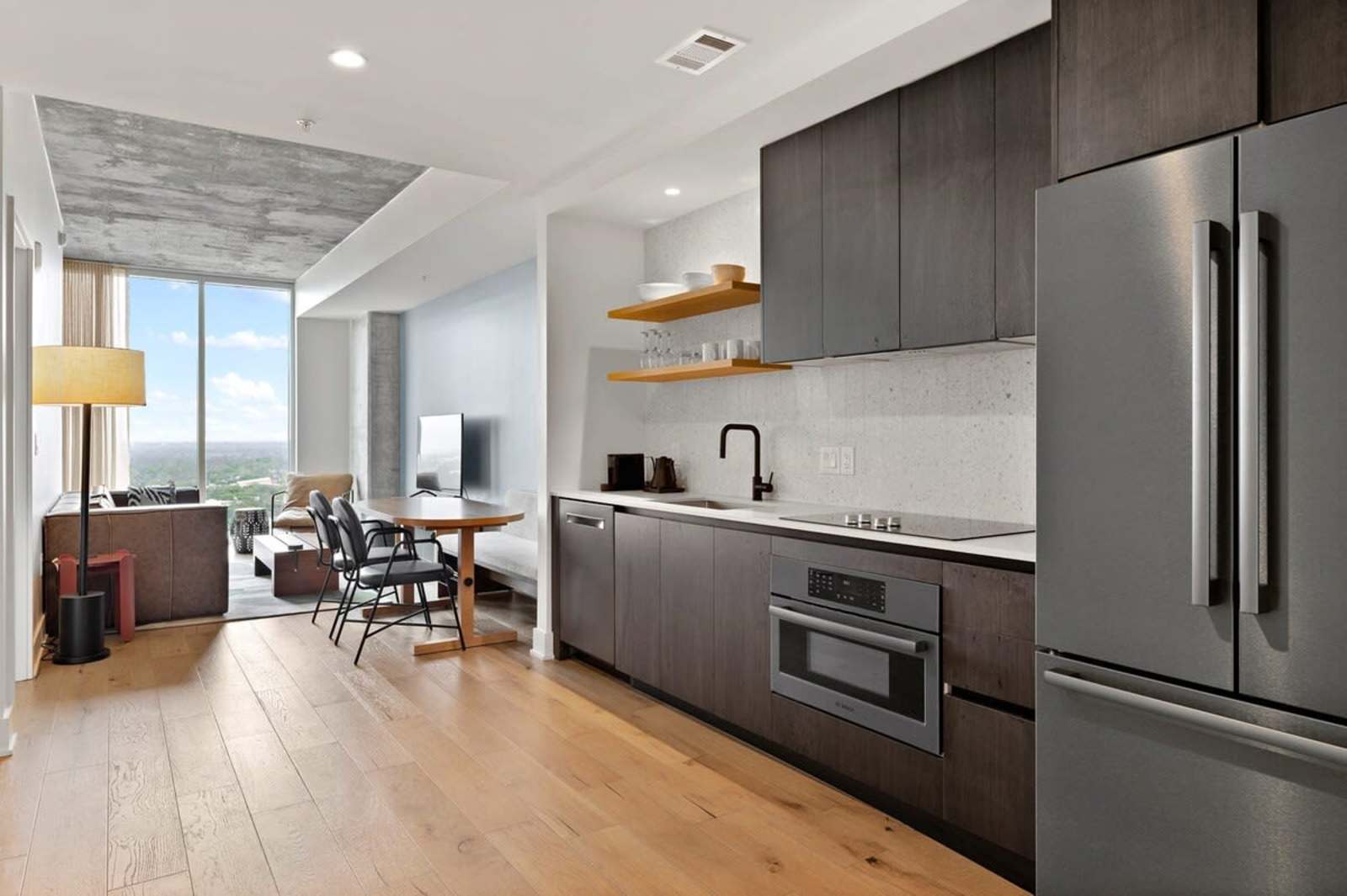 Open kitchen and living area in unit 2006 seen along the length of the condo toward the window wall