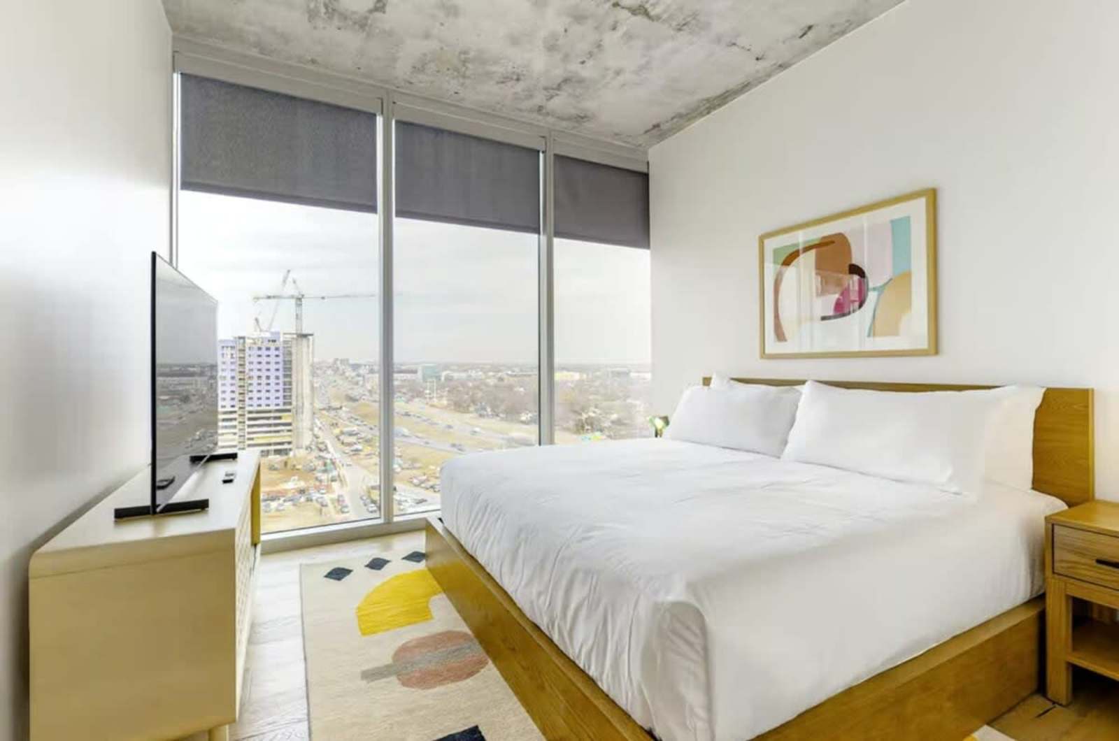 King bed in unit 1205 facing the television, with the skyline visible through the window