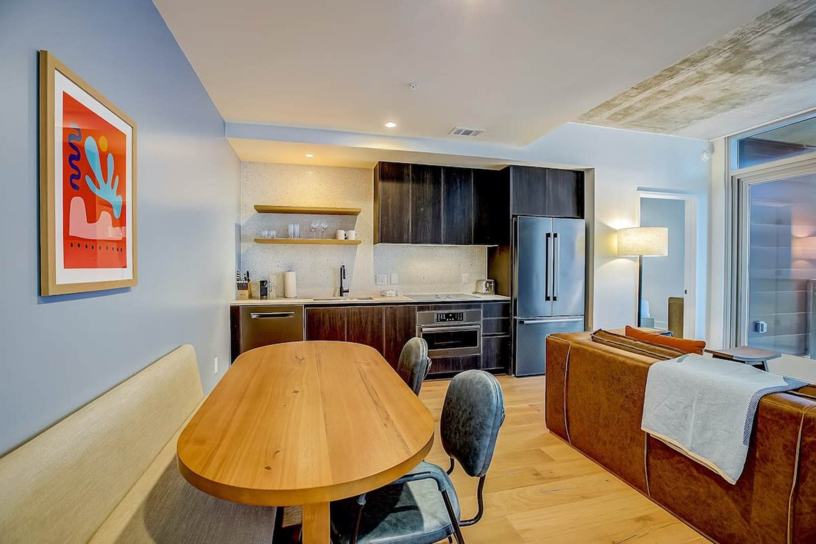 Dining table and open kitchen in unit 1406, with the balcony door and living area beyond
