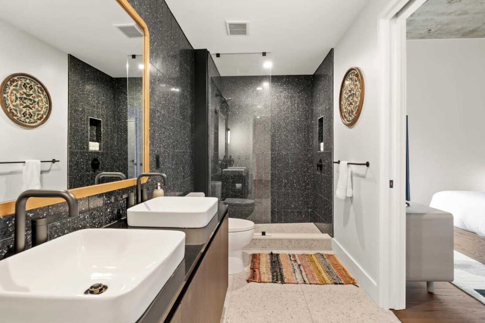 Walk-in shower and double vanity in unit 1804, finished in dark speckled tile
