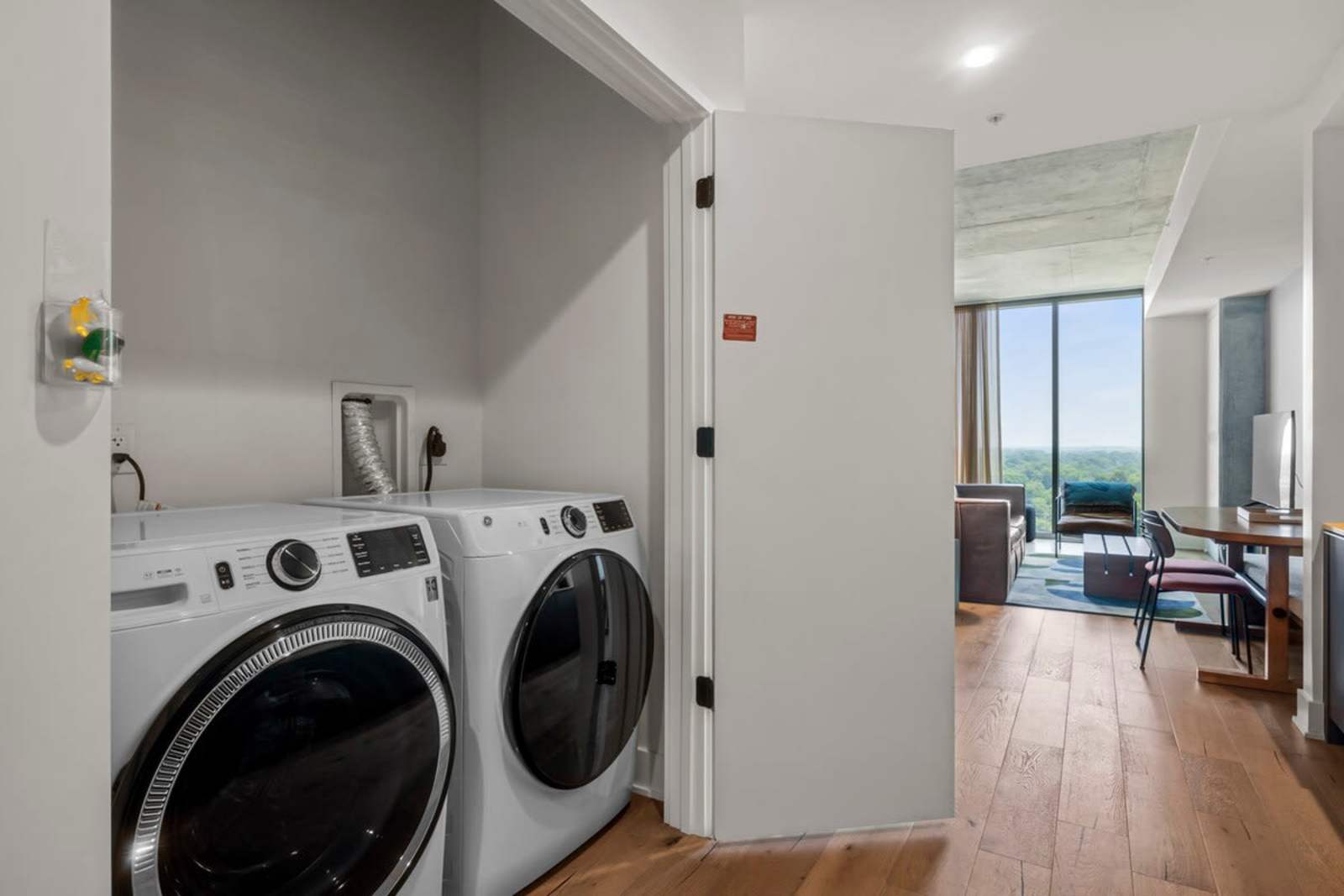 Full-size side-by-side washer and dryer in unit 1409, with the living room beyond
