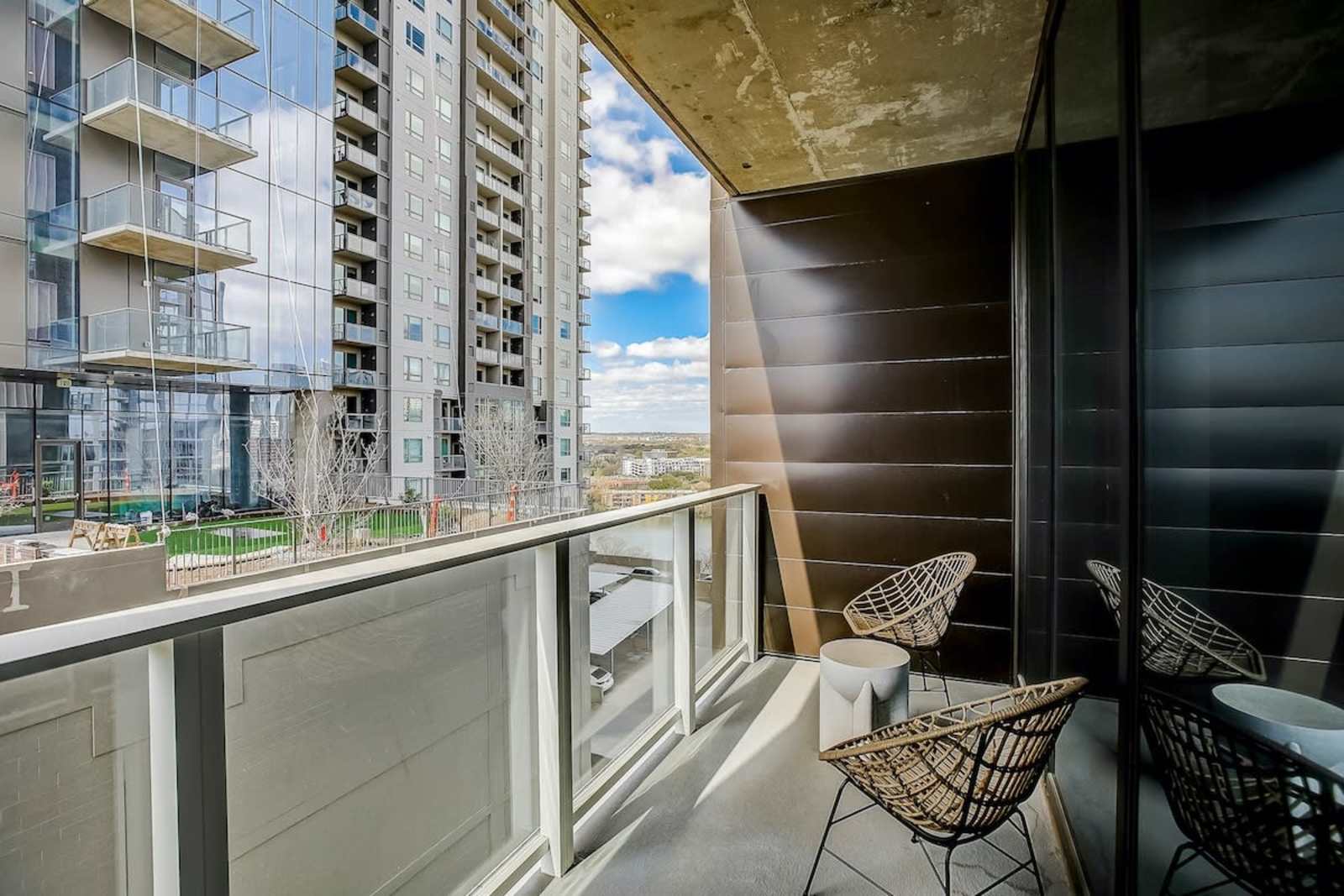 Private balcony of unit 1406 with two chairs and a side table, looking out at the neighbouring towers