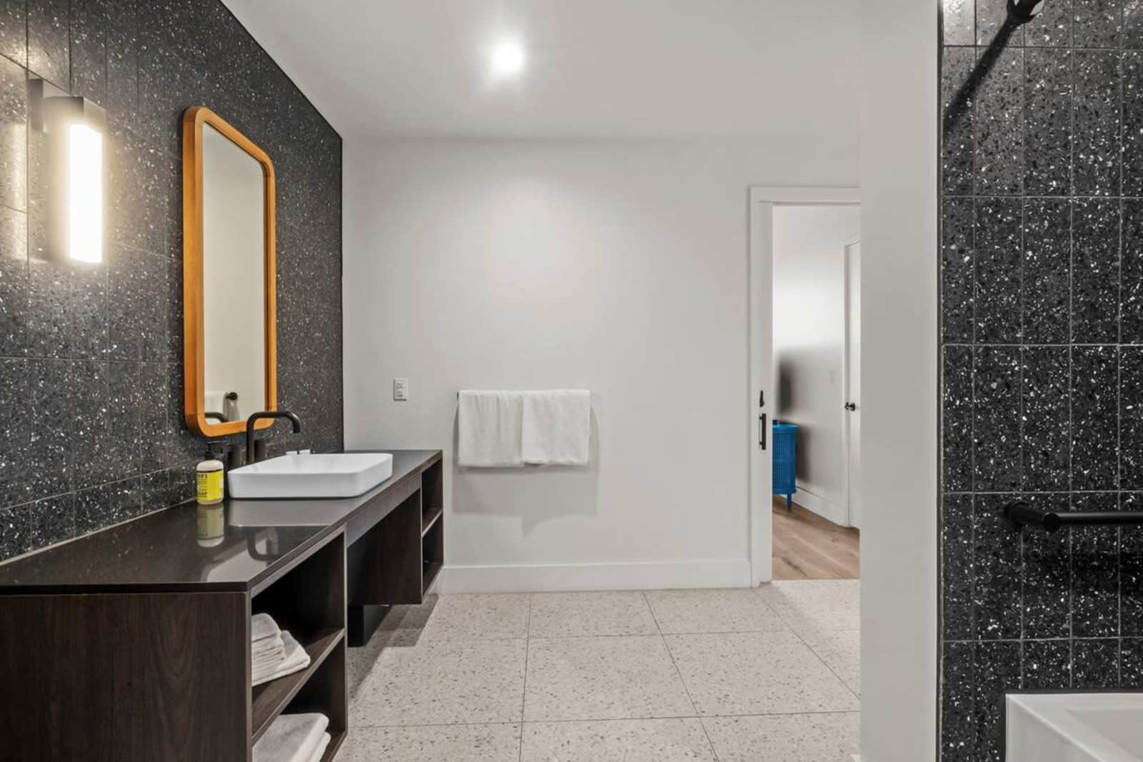 Walk-in shower and vanity in unit 1409 with grab rails and terrazzo flooring